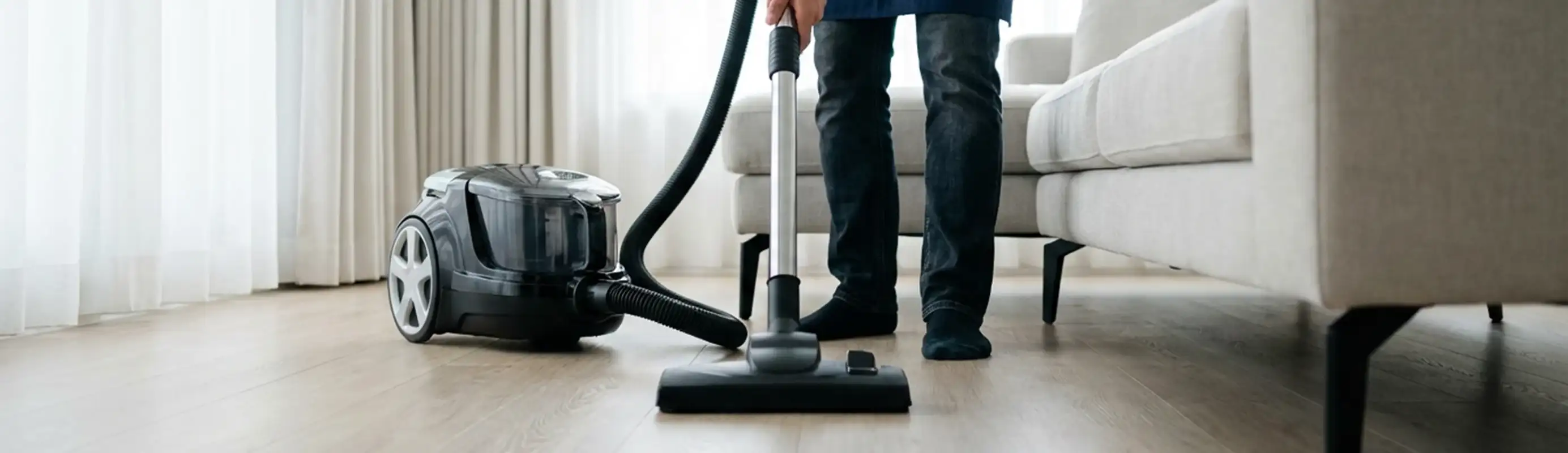 Professional house cleaner vacuuming a living room floor with a canister vacuum cleaner, Knoxville, TN.